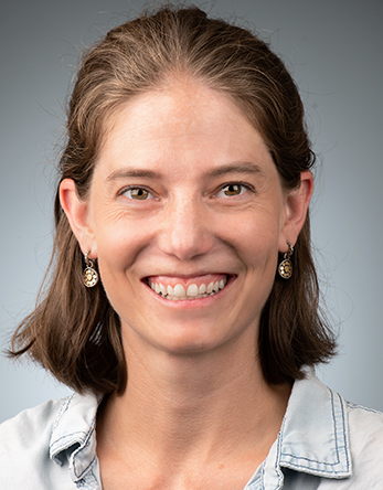 Studio headshot of a smiling woman with shoulder-length brown hair